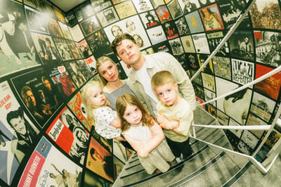 Andy Sommer, Morgan and their three kids standing in a Tokyo alley lined floor to ceiling with music posters