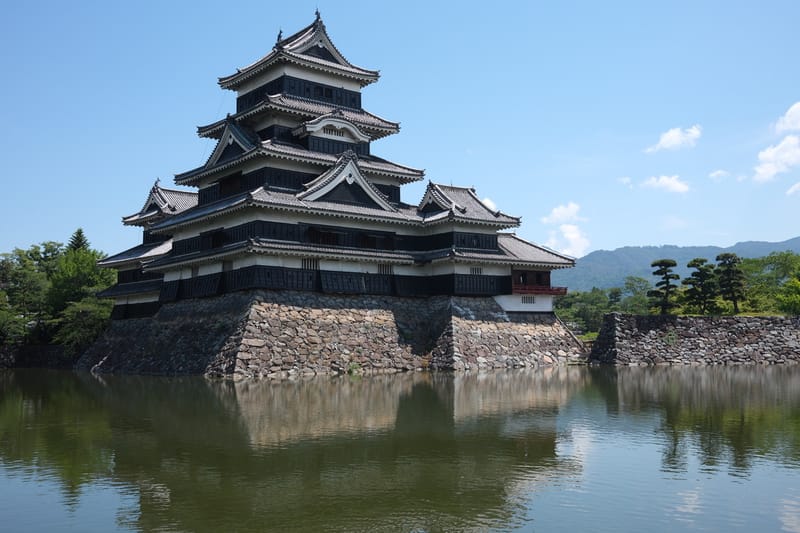 Matsumoto Castle, its black keep reflected in the surrounding moat on a clear day