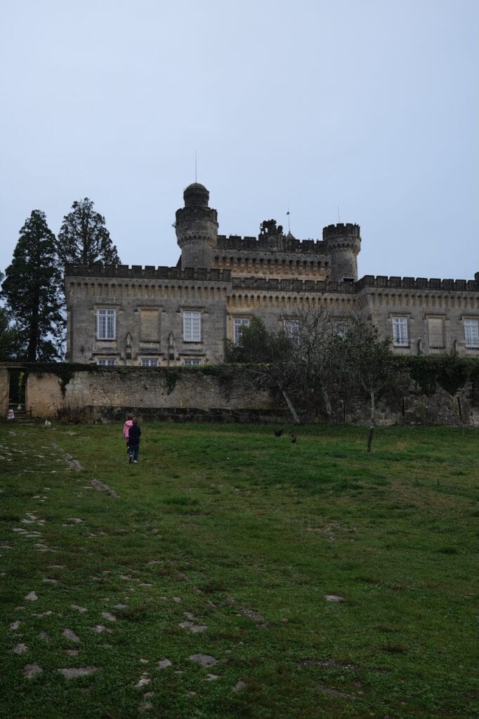 A stone chateau behind a wide lawn in the Bordeaux countryside.