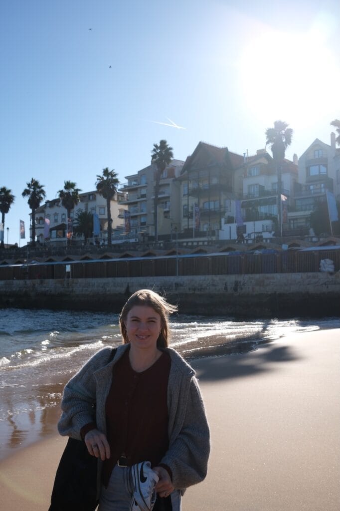 A person by a fountain in a sunlit Lisbon plaza.
