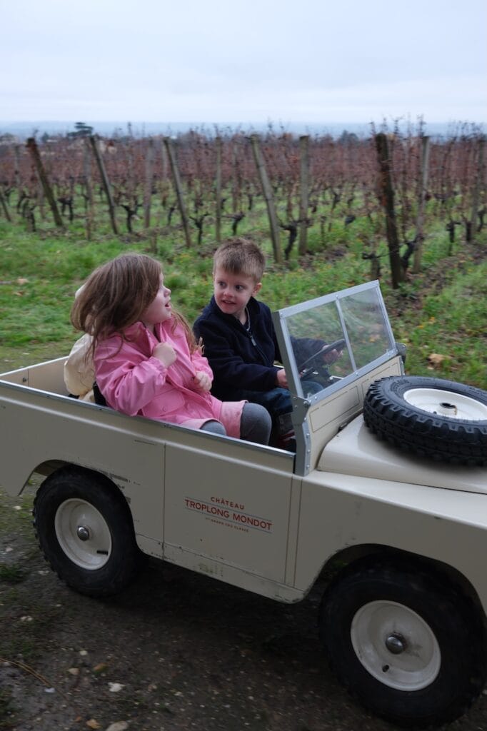 A Sommer child driving a toy jeep through a vineyard.