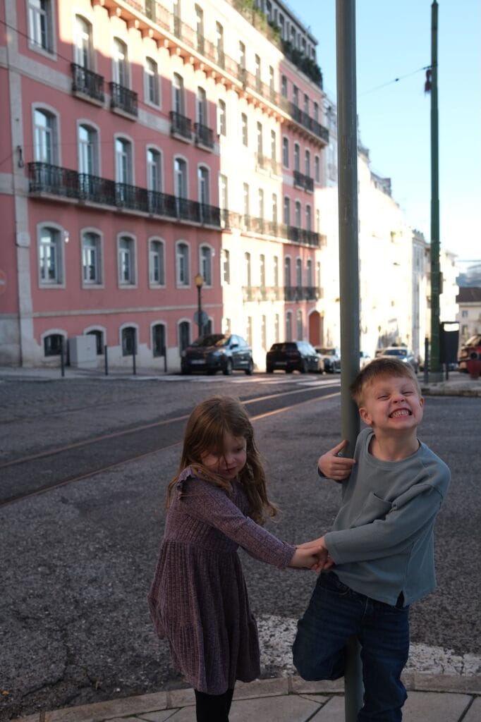 Children on a colorful street lined with red and pink buildings.