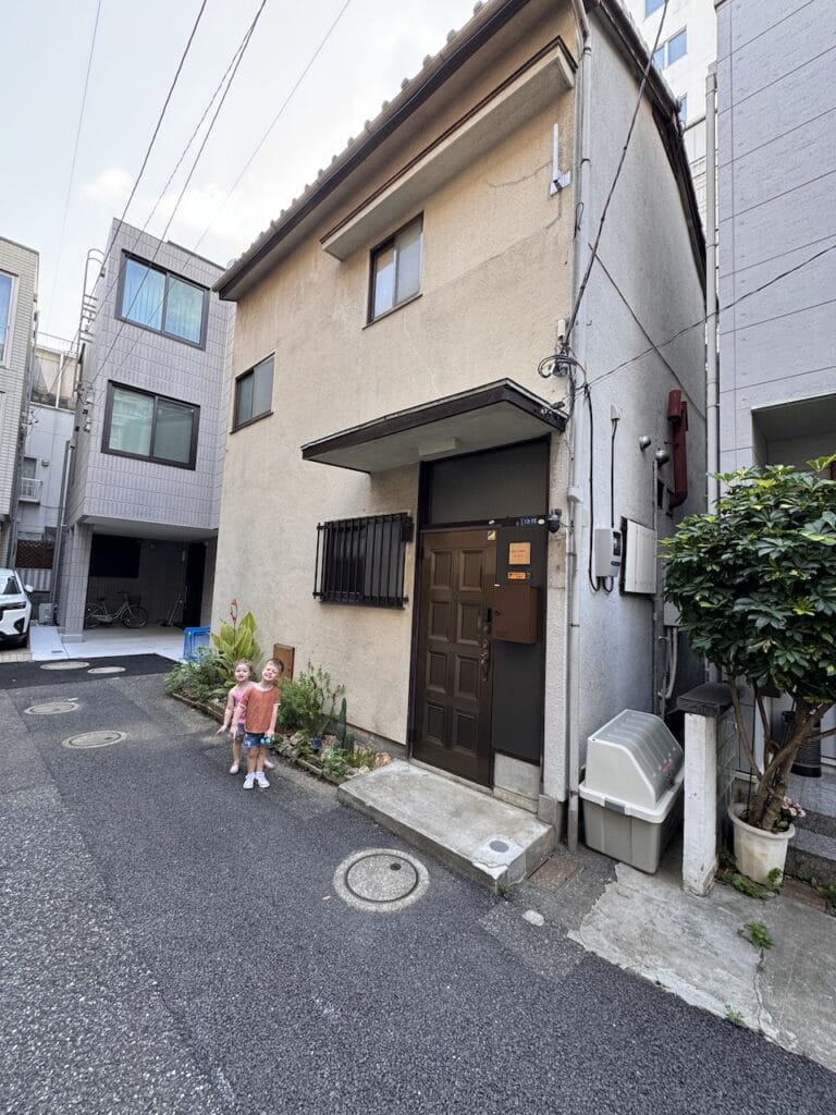 A quiet residential street in Japan with a small child by a doorway.