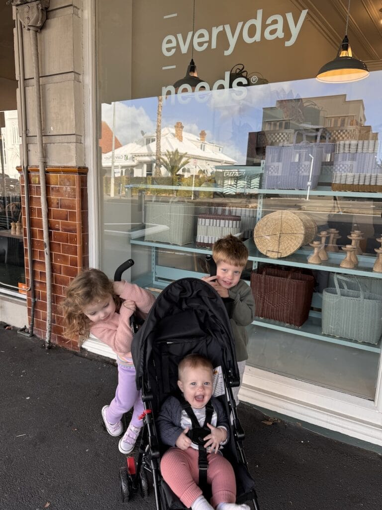 Children outside an everyday goods shop with a stroller.